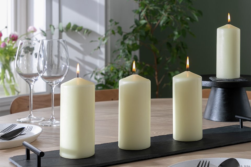 Four Habitat large pillar candles in ivory colour on a dinner table.